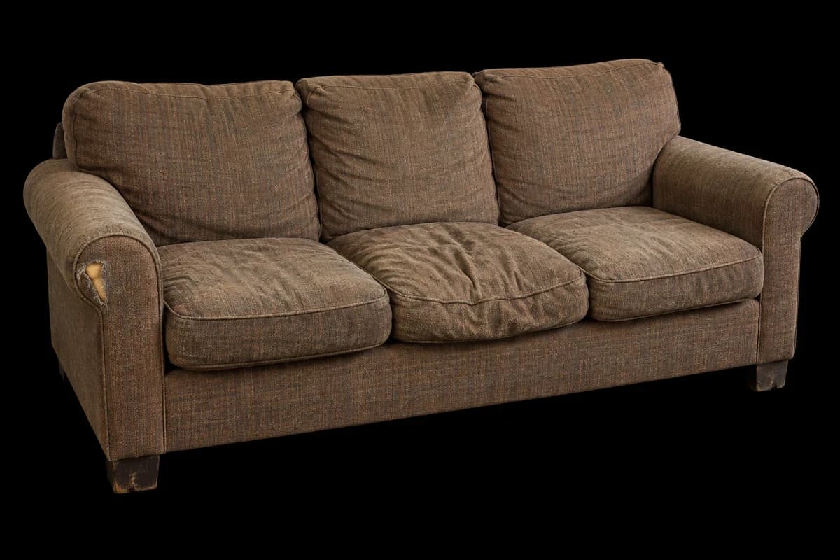 Sena trivietė sofa Sena tiesi sofa įdubusiomis pagalvėmis ir praplyšusiu porankiu.